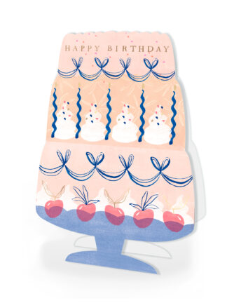 handgjort födelsedagskort formgivet som en trevånings tårta med texten 'HAPPY BIRTHDAY', blå dekorband, tända spiralljus, vispad grädde och röda körsbär på ett blått tårtställ