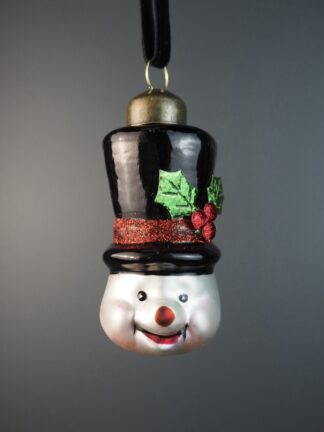 julkula snögubbe hängande som ett leende snögubbehuvud med svart hatt, gröna blad och röda bär