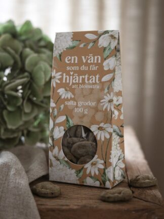 blommigt paket med majas godsaker salta grodor 100 g, runt plastfönster som visar godis på ett träbord