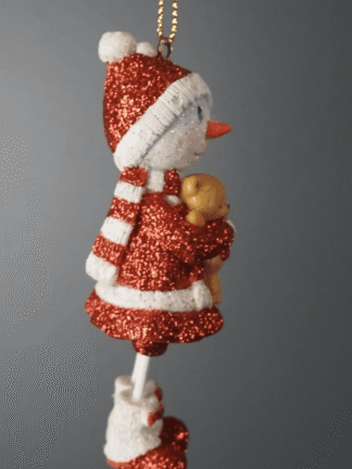 hängande julkula snögubbe i rött och vitt med glitter som håller en liten nalle