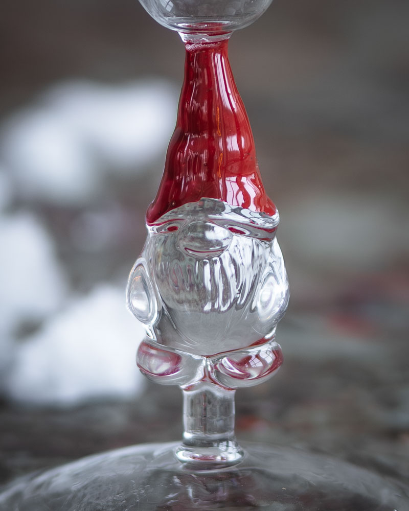 närbild på tomte ljusstake glas med klar kropp och röd luva