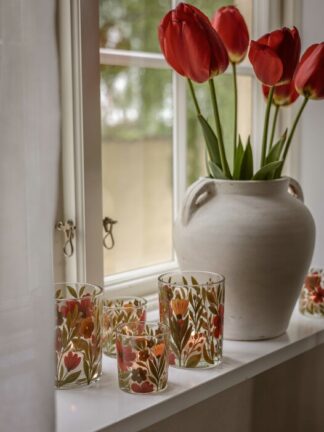 Majas lykta Autumn Blossom på fönsterbräda med flera glaslyktor i höstligt blommönster framför en vit vas med röda tulpaner