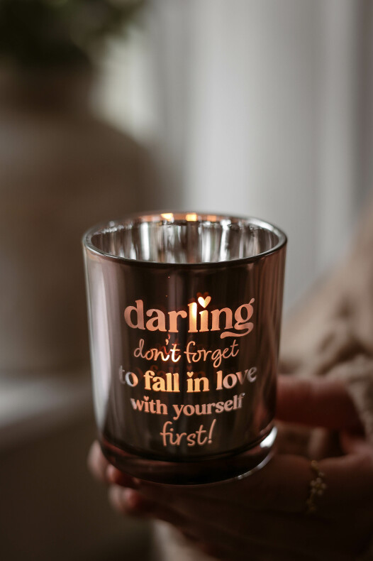 majas lykta darling, tänd glaslykta med texten "darling don't forget to fall in love with yourself first" som sprider ett varmt sken