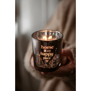 hand håller en glasljuslykta med text 'home is my happy place' och dekorativa husmotiv; ljuslykta med text som ger varmt sken.