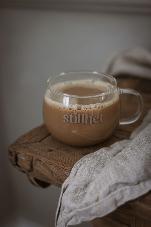 majas glasmugg stillhet - rund glasmugg med texten "stillhet" fylld med kaffe på ett rustikt träbord bredvid en linneservett